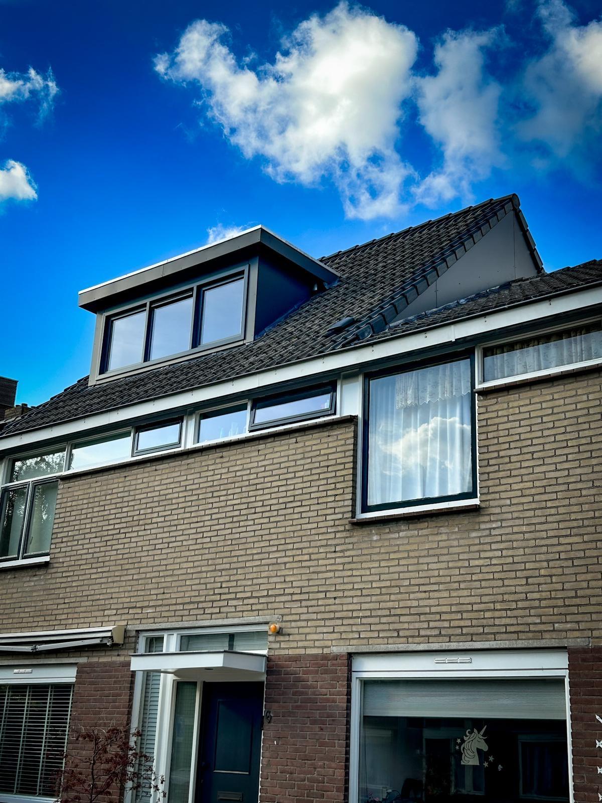 Woninggevel met een nieuw dakkapel met zwarte kozijnen.