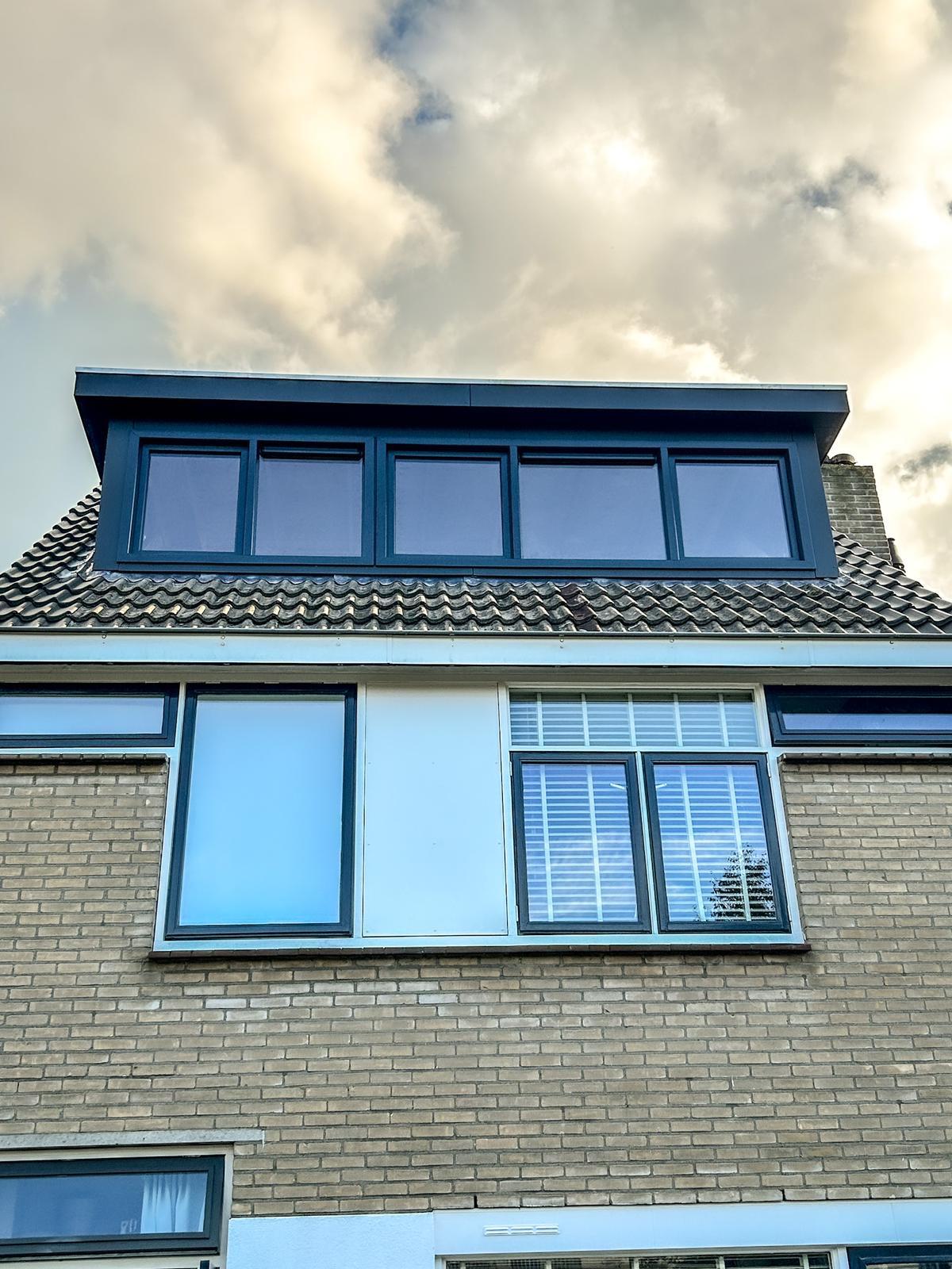 Donkere dakkapel met vier ramen op een woonhuis.