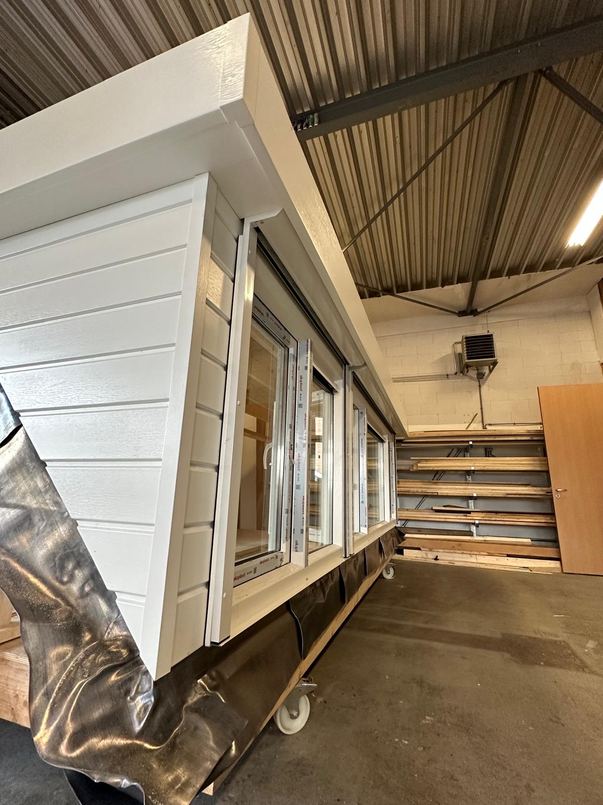 Prefab bouwelement met ramen in een werkplaats.