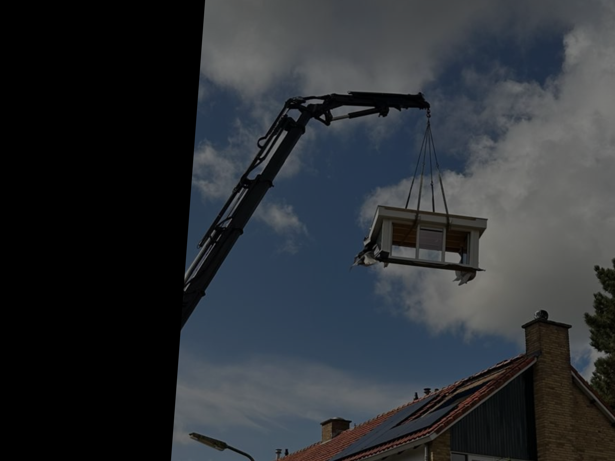 Kraan hijst een bouwelement boven een dak.